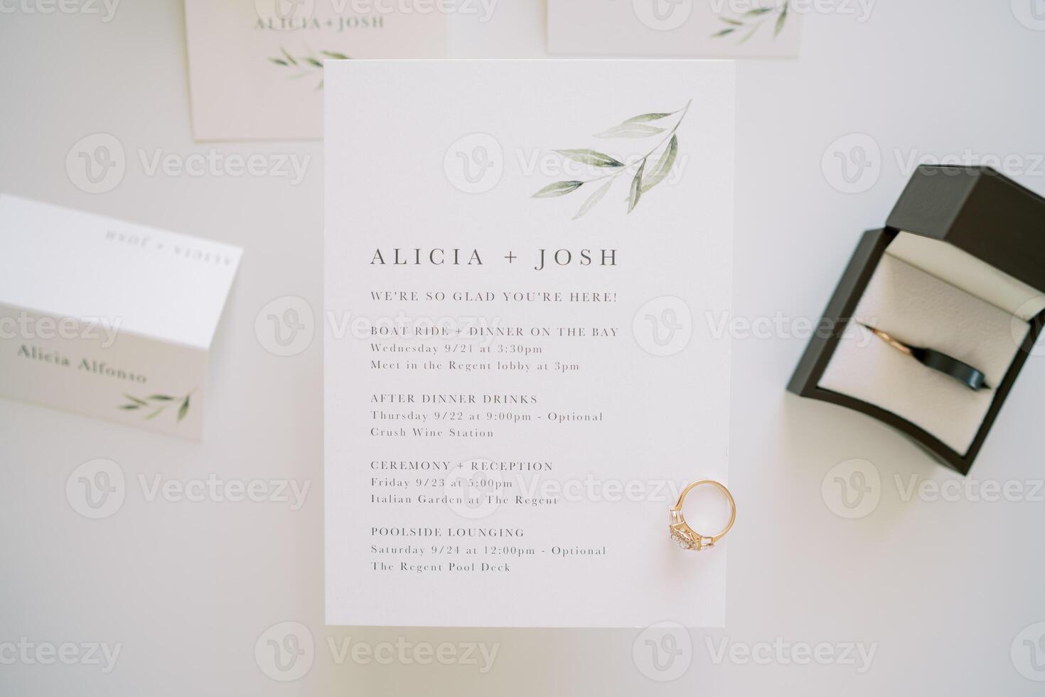 Engagement ring lies on a wedding invitation next to a box and name cards photo
