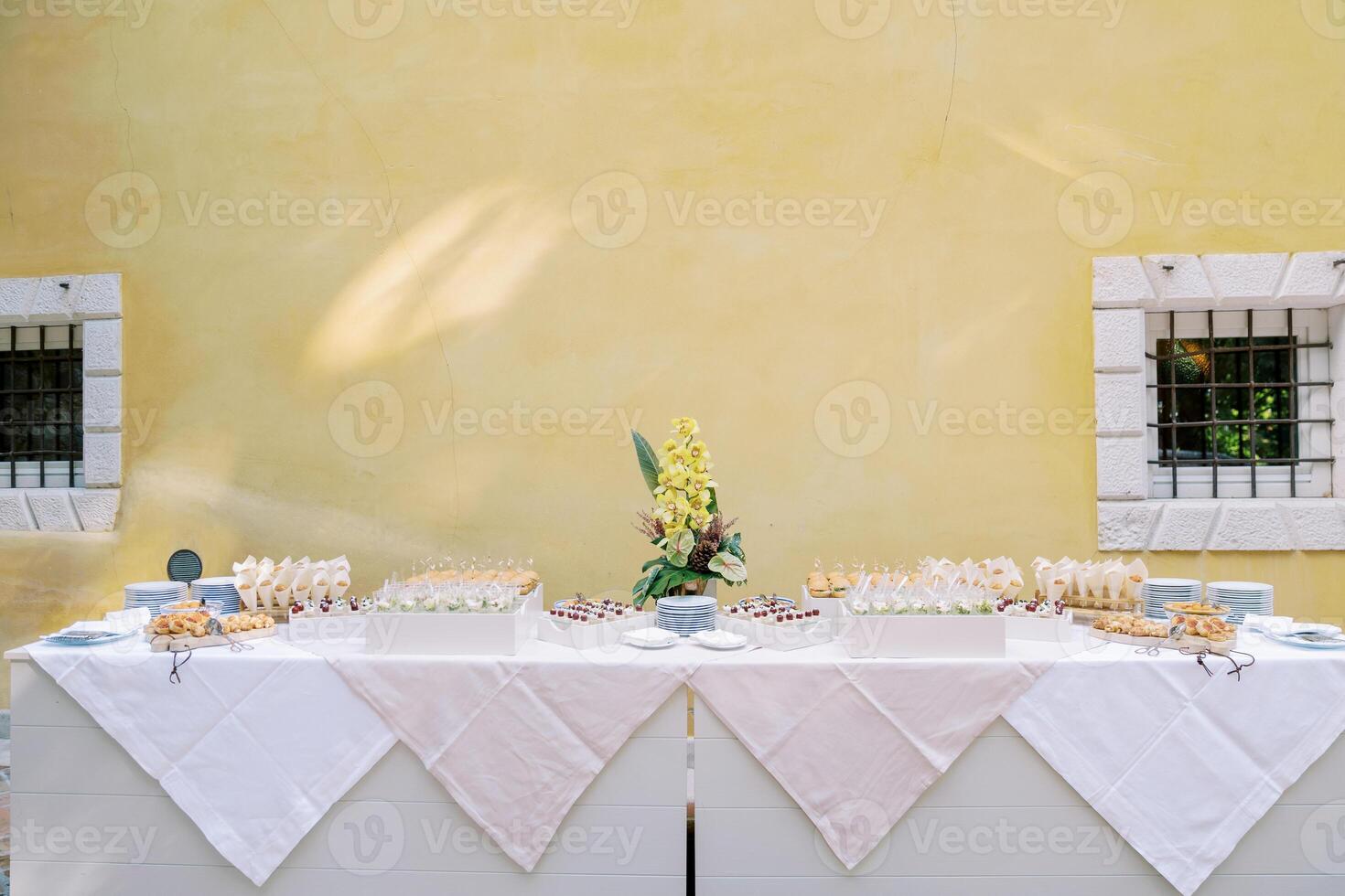 Buffet with small snacks and sandwiches stands against the wall of the building photo
