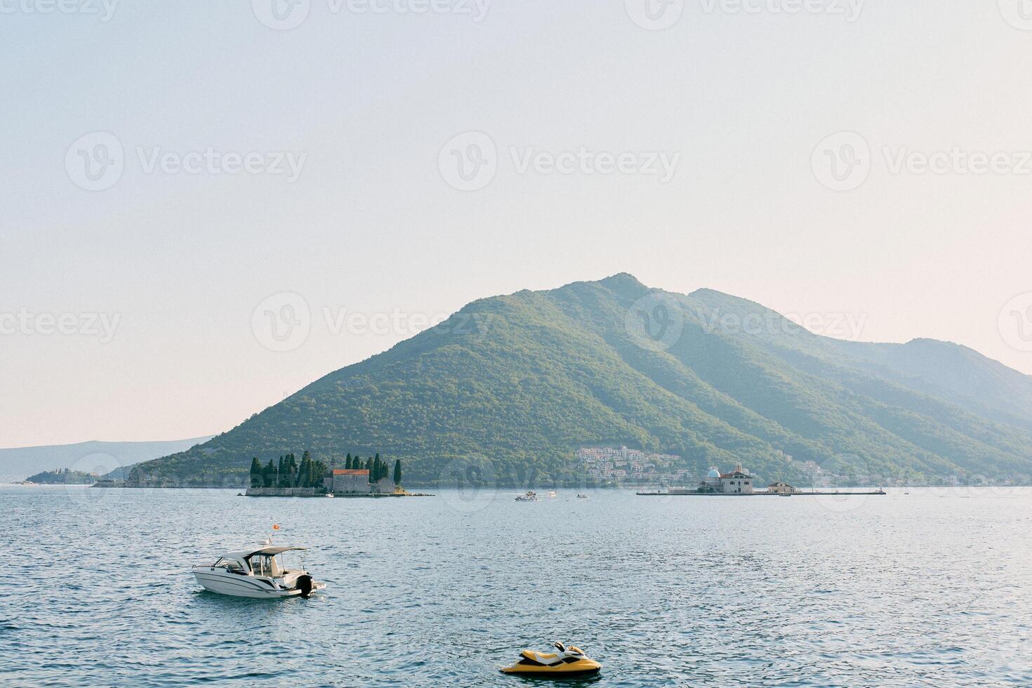 Motor boats are moored in the sea with St. George Island and the mountains in the background. Montenegro photo