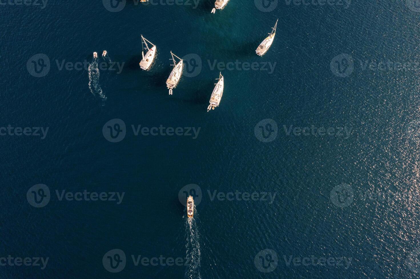 Motor boat sails across the sea towards a sailing regatta. Top view photo