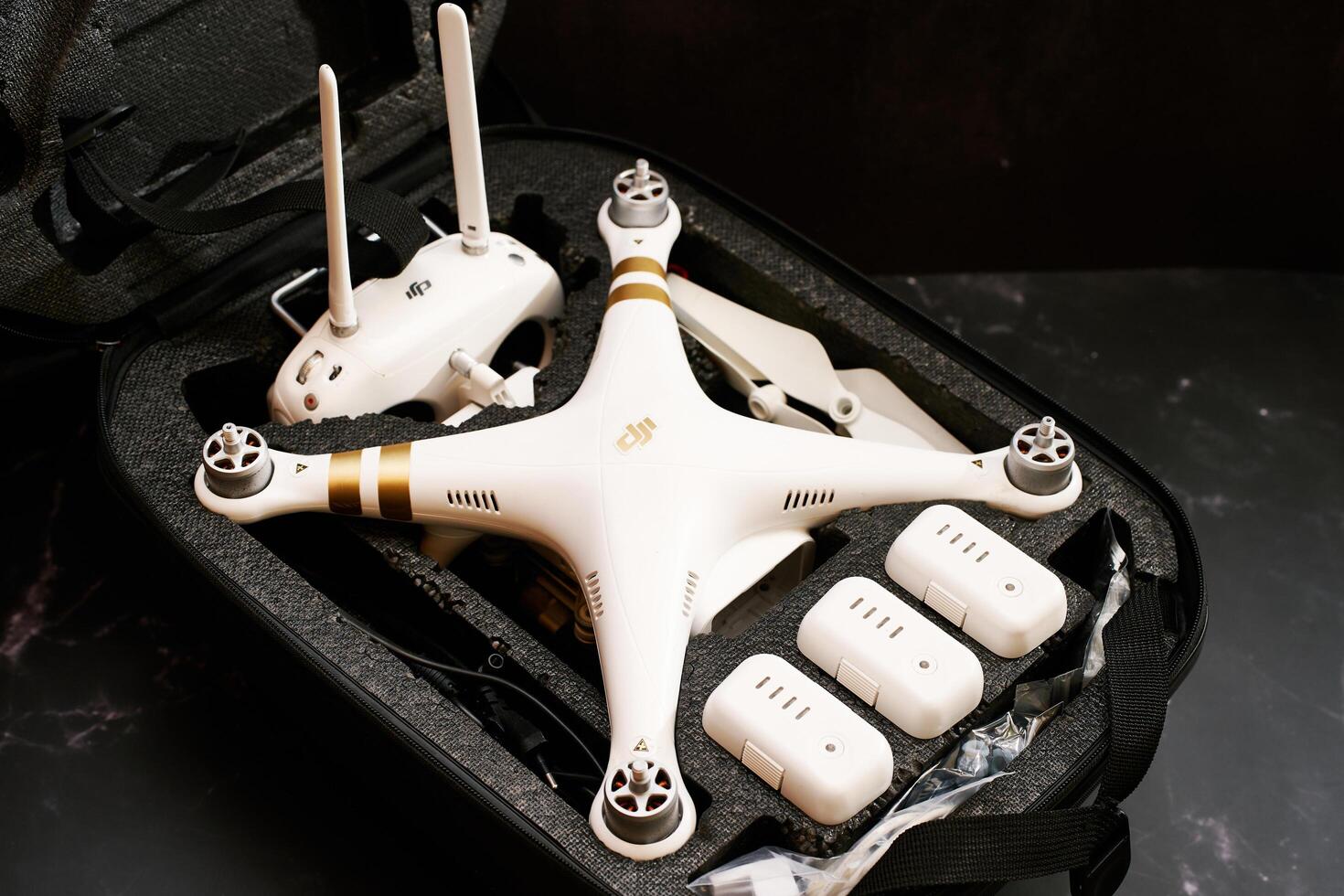 USA, Arizona - March 10, 2025. White DJI Phantom 3 drone with spare batteries and a control panel lies in a protective case on a black table photo