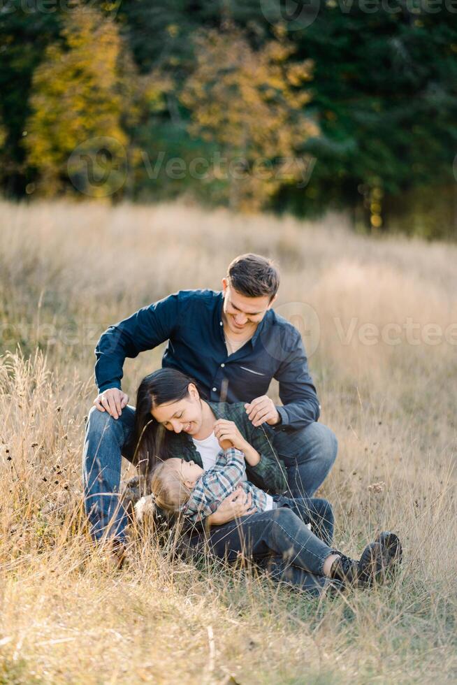 Dad sits behind mom with a little girl on her lap and looks at her photo