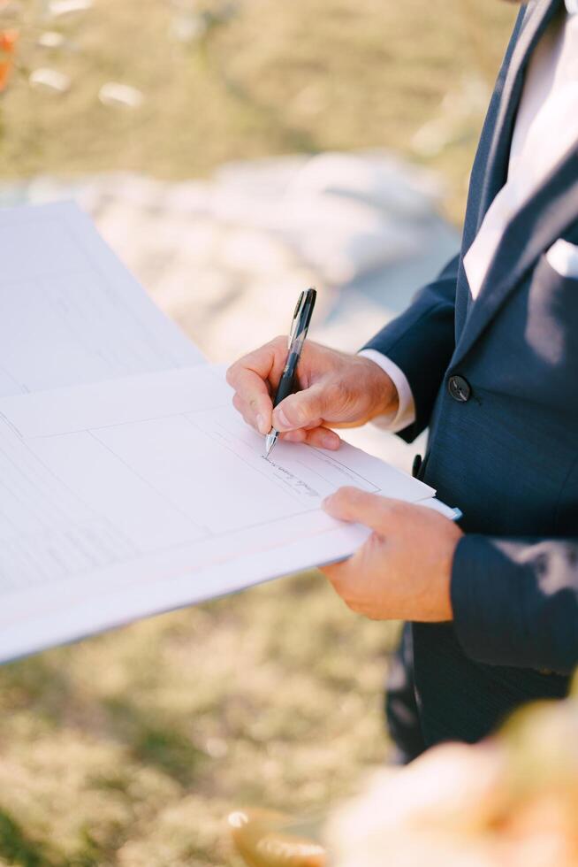 Montenegro, Budva - July 05, 2024. Groom puts his signature in the marriage registration book. Cropped. Faceless photo