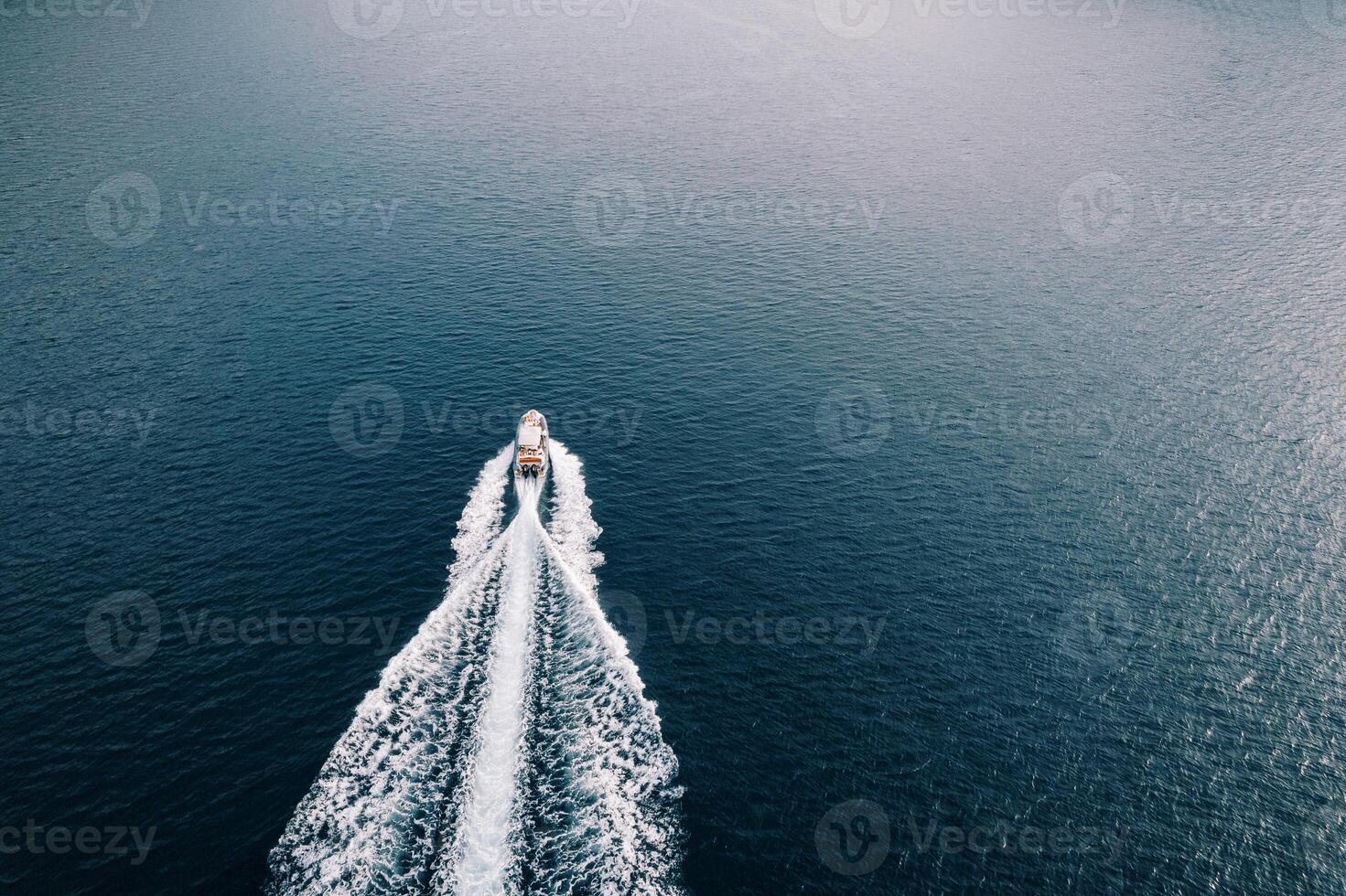 Speedboat sails across the sea leaving a white foamy trail. Back view. Drone photo