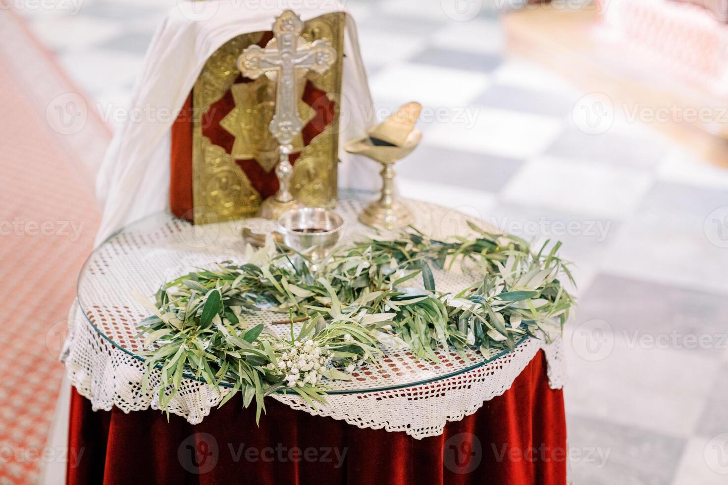 Green wreaths lie on the table next to silver bowls, a cross and a bible in the church photo