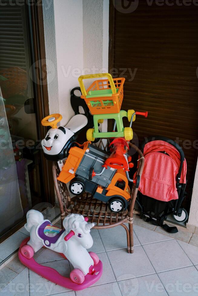Colorful children toys lie on a chair on the balcony against the wall photo