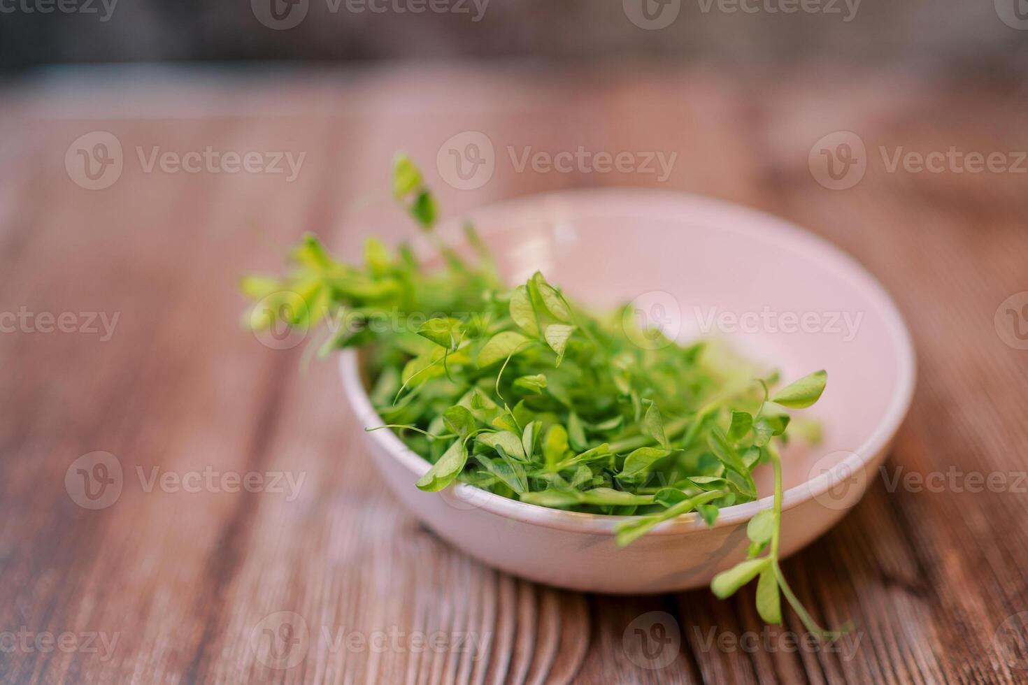 Young green sprouts of microgreen peas lie in a plate on the table photo