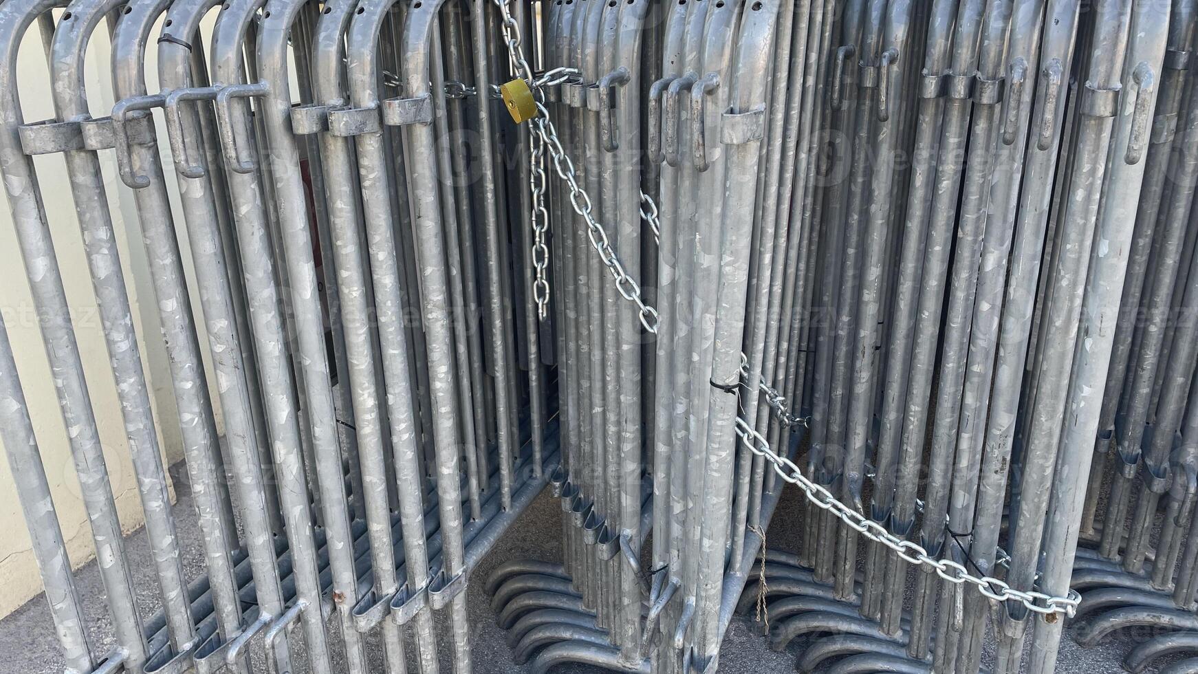 Metal barriers securely chained together on a sunny day in an outdoor setting, symbolizing order and organization photo