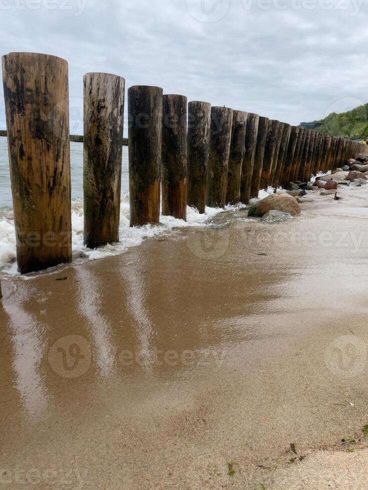 Weathered wooden posts stand strong along the serene shoreline, inviting tranquility and reflection near the gentle waves photo