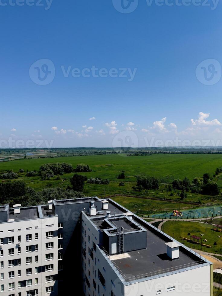 Overlooking vibrant green fields and modern architecture under a bright blue sky in a serene urban landscape photo
