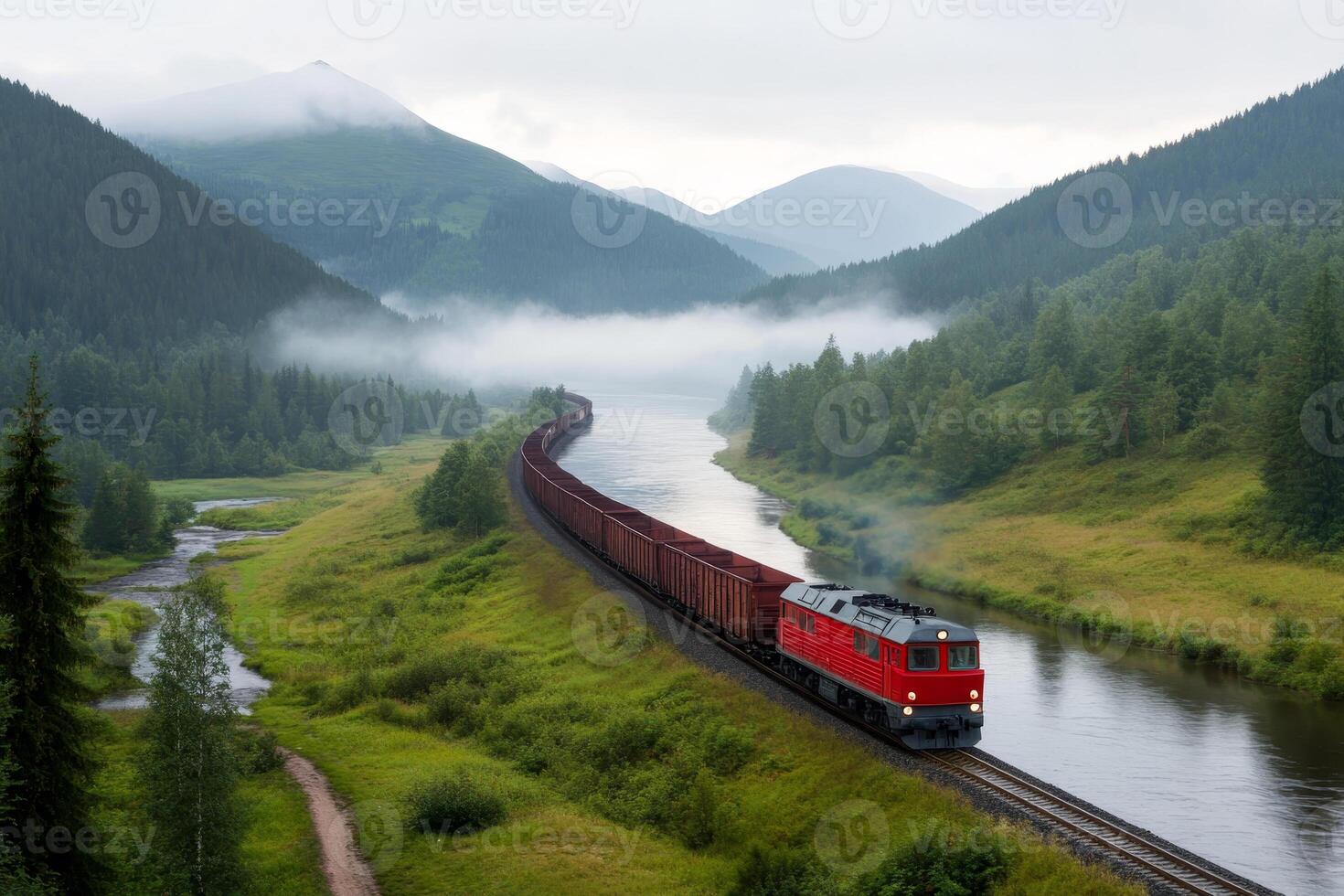 Train travels along a scenic river surrounded by misty mountains in a tranquil landscape during overcast weather photo