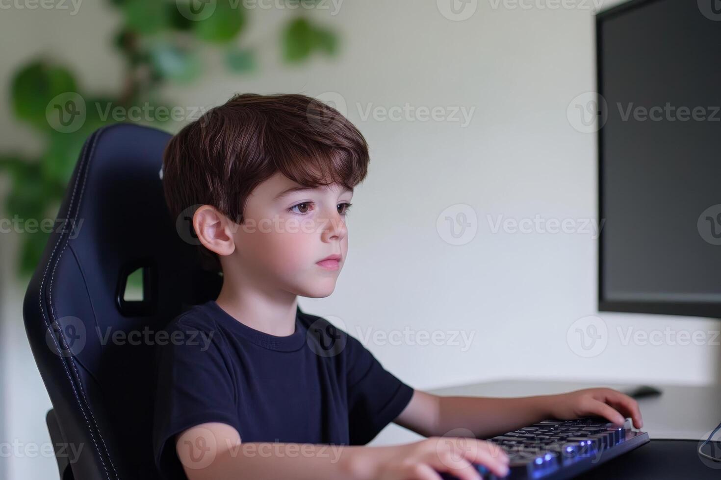 Young boy focused on computer work in a modern home office setting during the afternoon photo