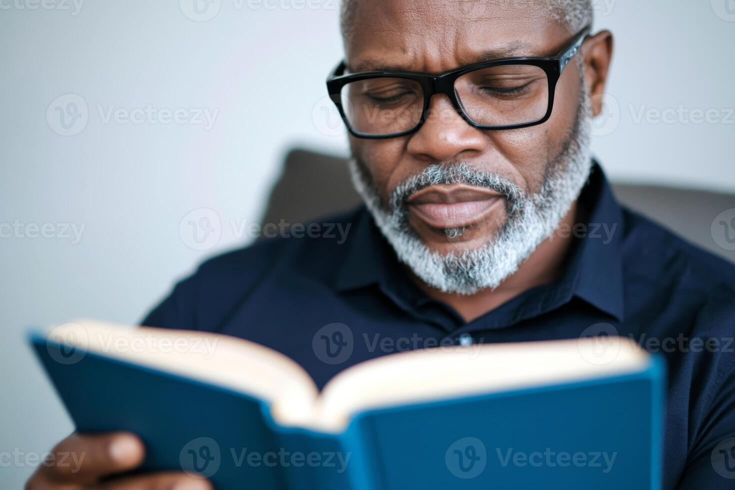 Man engaged in reading an interesting book while sitting comfortably in a chair at home during daylight hours photo