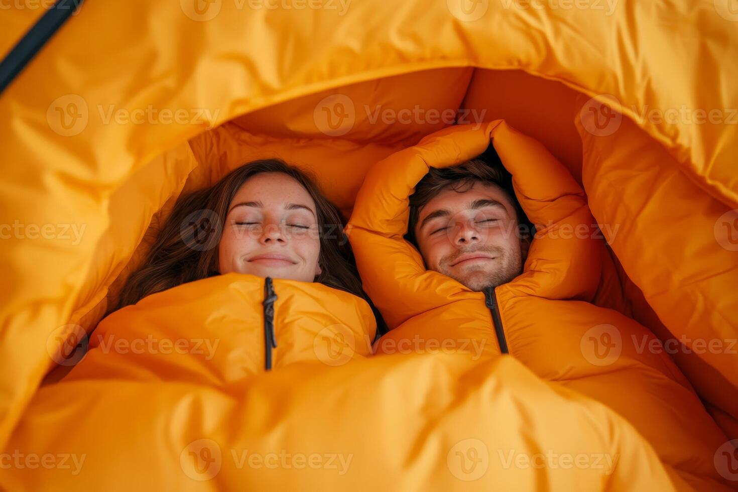 Cozy couple enjoying time together in bright sleeping bags while camping in nature during cool evening hours photo