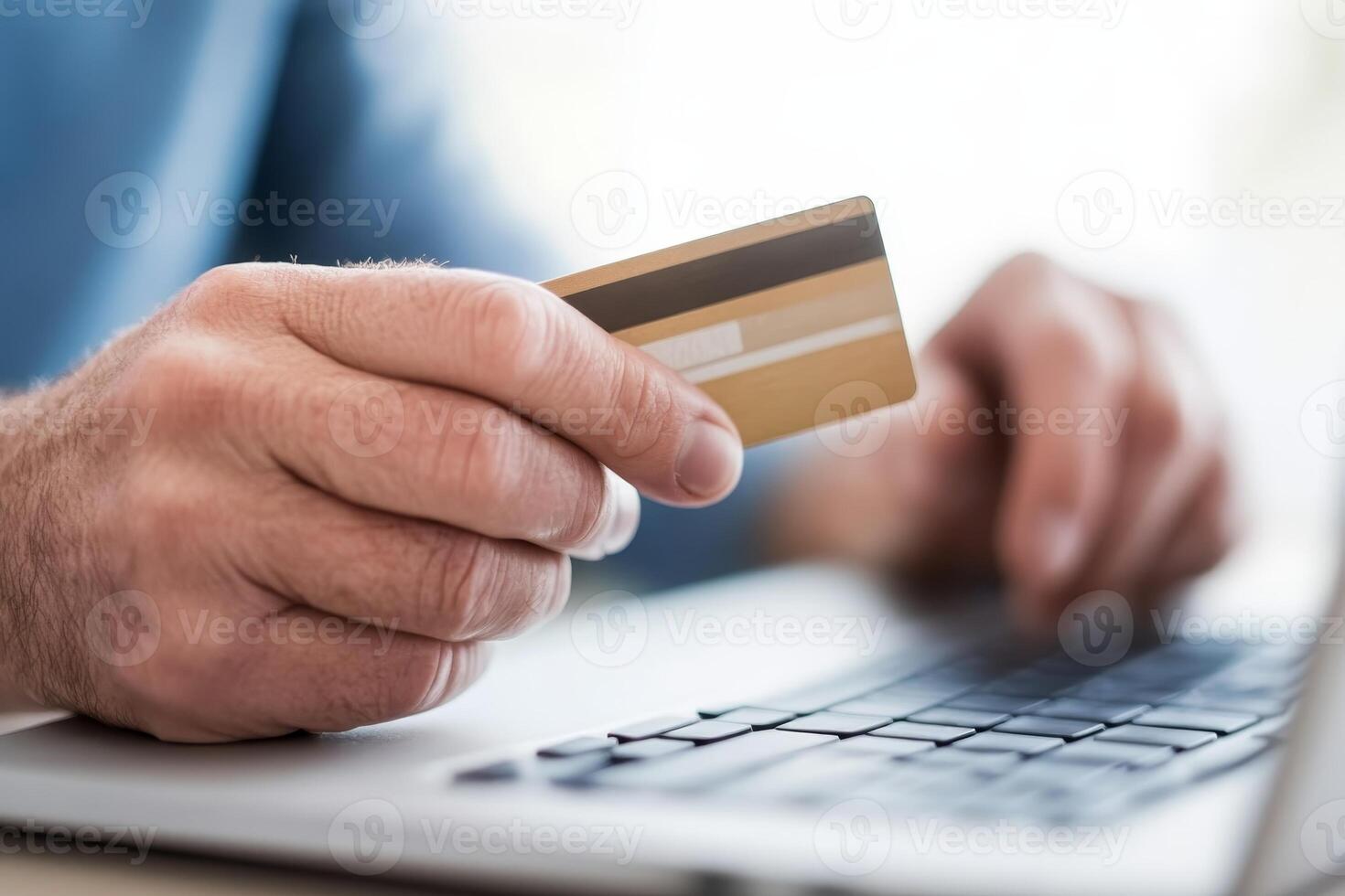 User engages in online shopping with credit card in hand while sitting at laptop desk photo