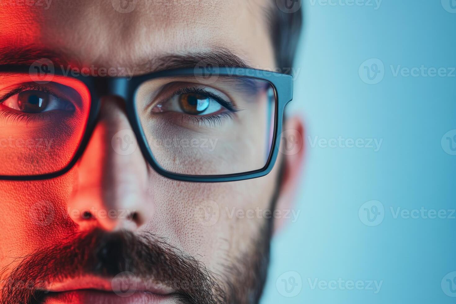 Close-up of a man with glasses showcasing well-defined facial features and captivating eyes under colorful lighting at dusk photo