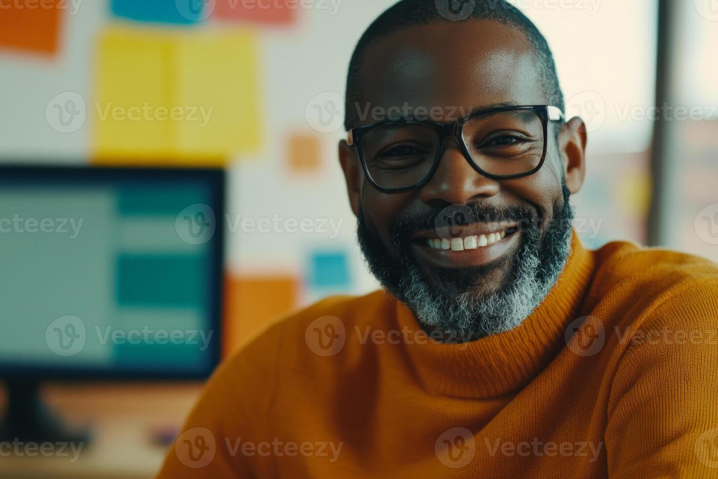 Smiling man in orange sweater at a creative workspace during the day with colorful sticky notes in the background photo