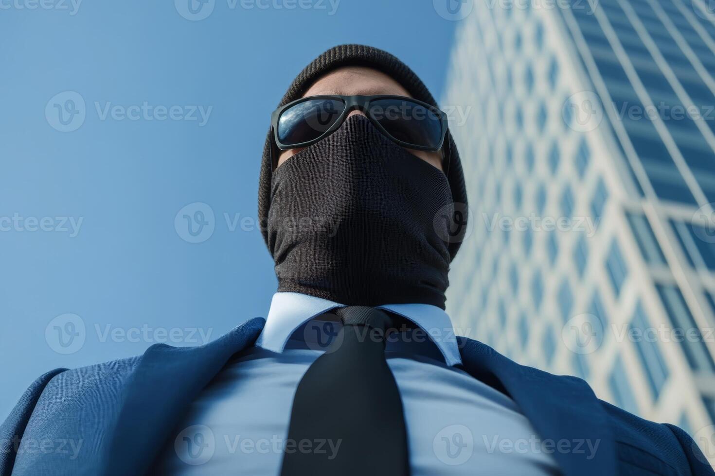Businessman wearing sunglasses and a mask stands confidently in a modern urban setting during daylight hours photo