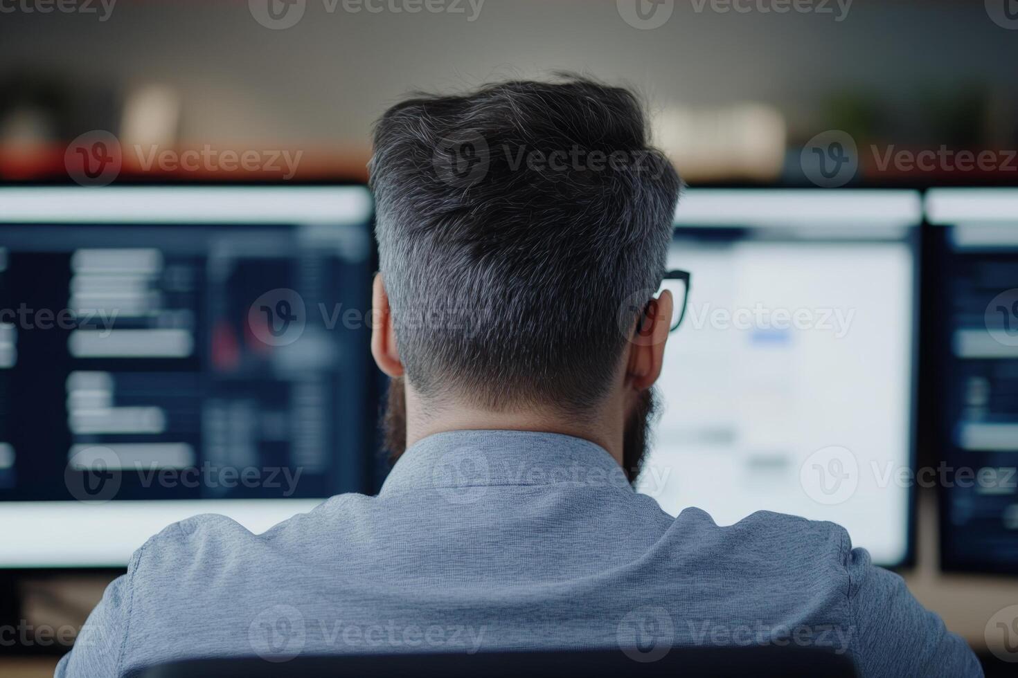 Person working on multiple computer screens in a modern office setting during daytime photo