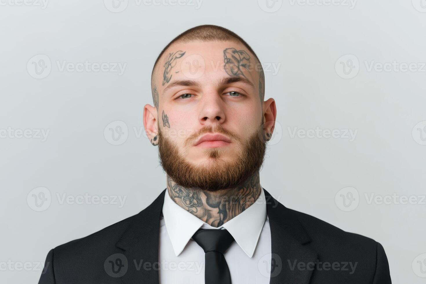Confident man with tattoos wearing a suit and tie in a neutral studio setting photo