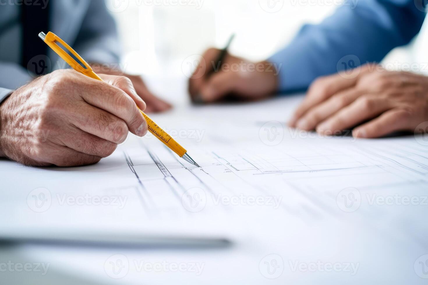 Professionals collaborating on architectural plans at a workspace during daytime hours photo
