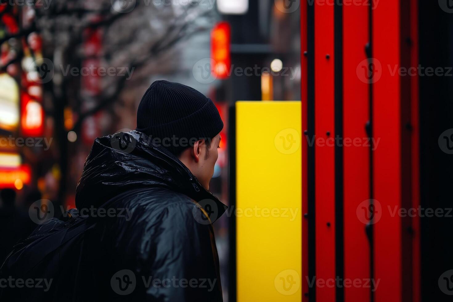Man in black jacket observing neon-lit street in urban setting during nighttime in a busy city atmosphere photo