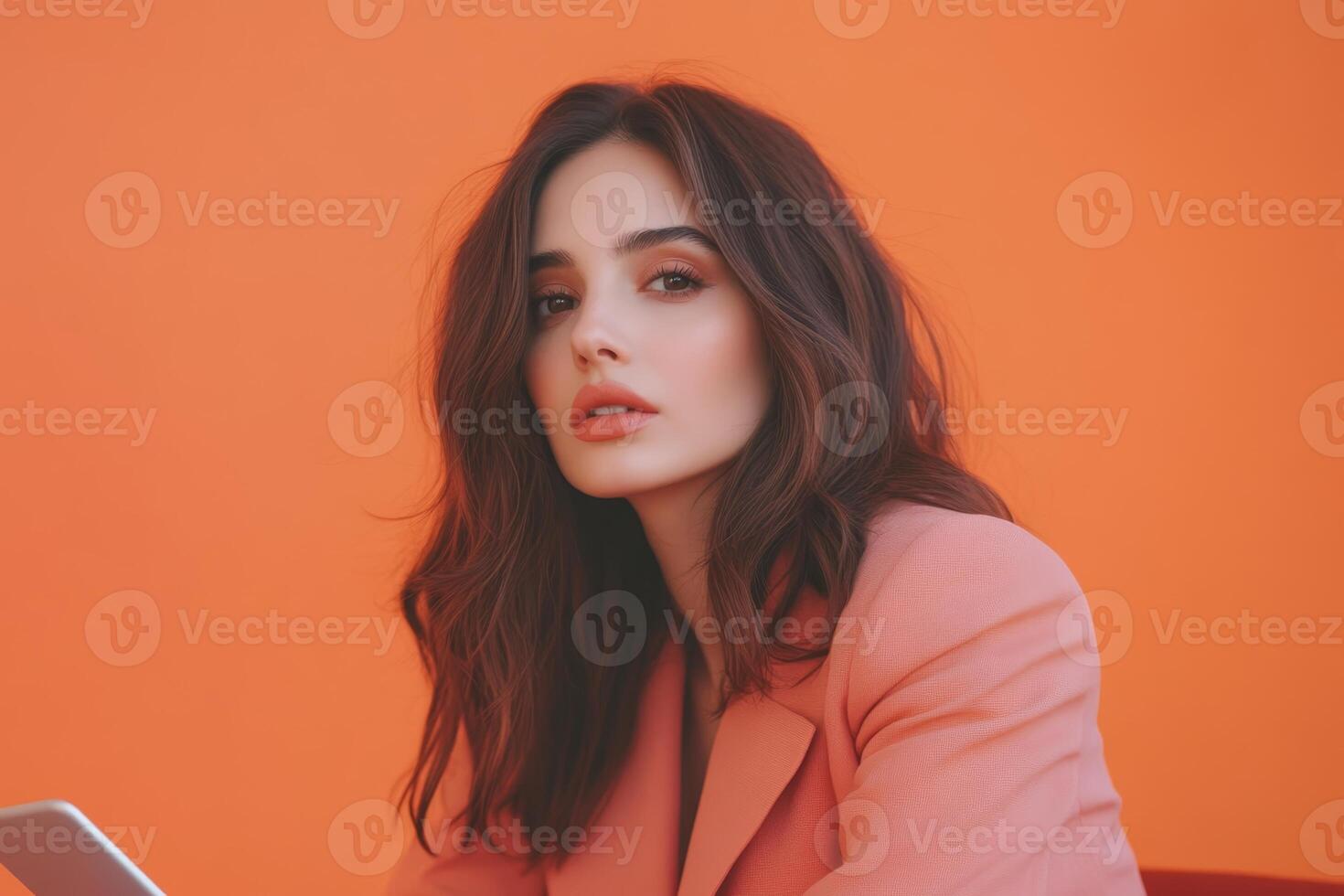 Model poses against a vibrant orange backdrop, showcasing a stylish pink blazer and a confident expression during a creative photoshoot photo