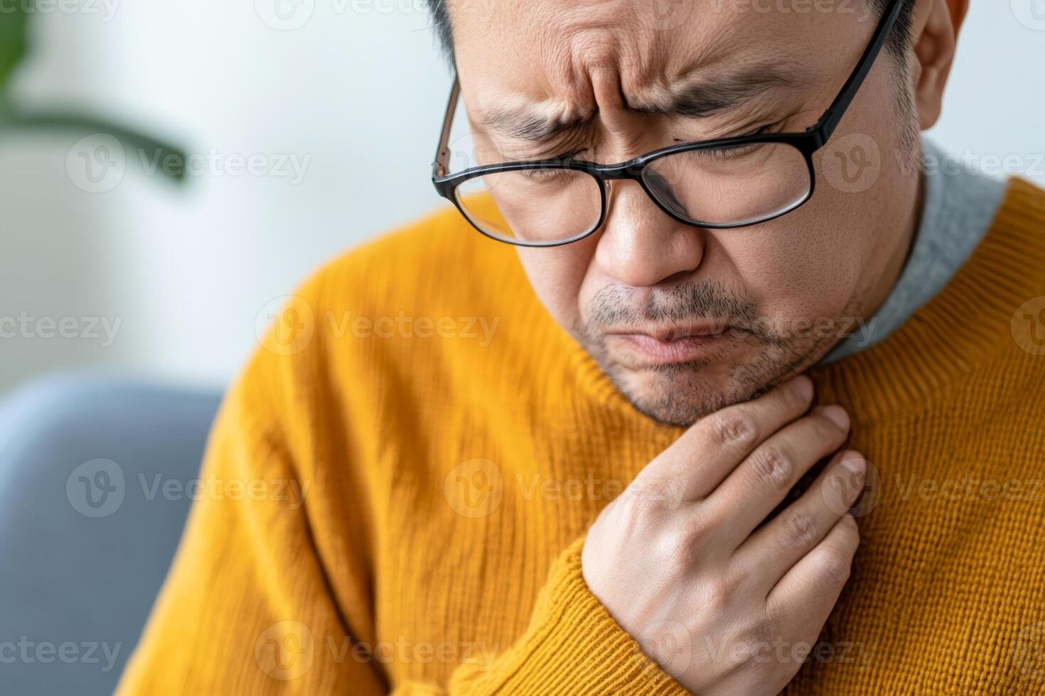 Man experiencing throat discomfort while sitting indoors in a cozy environment photo