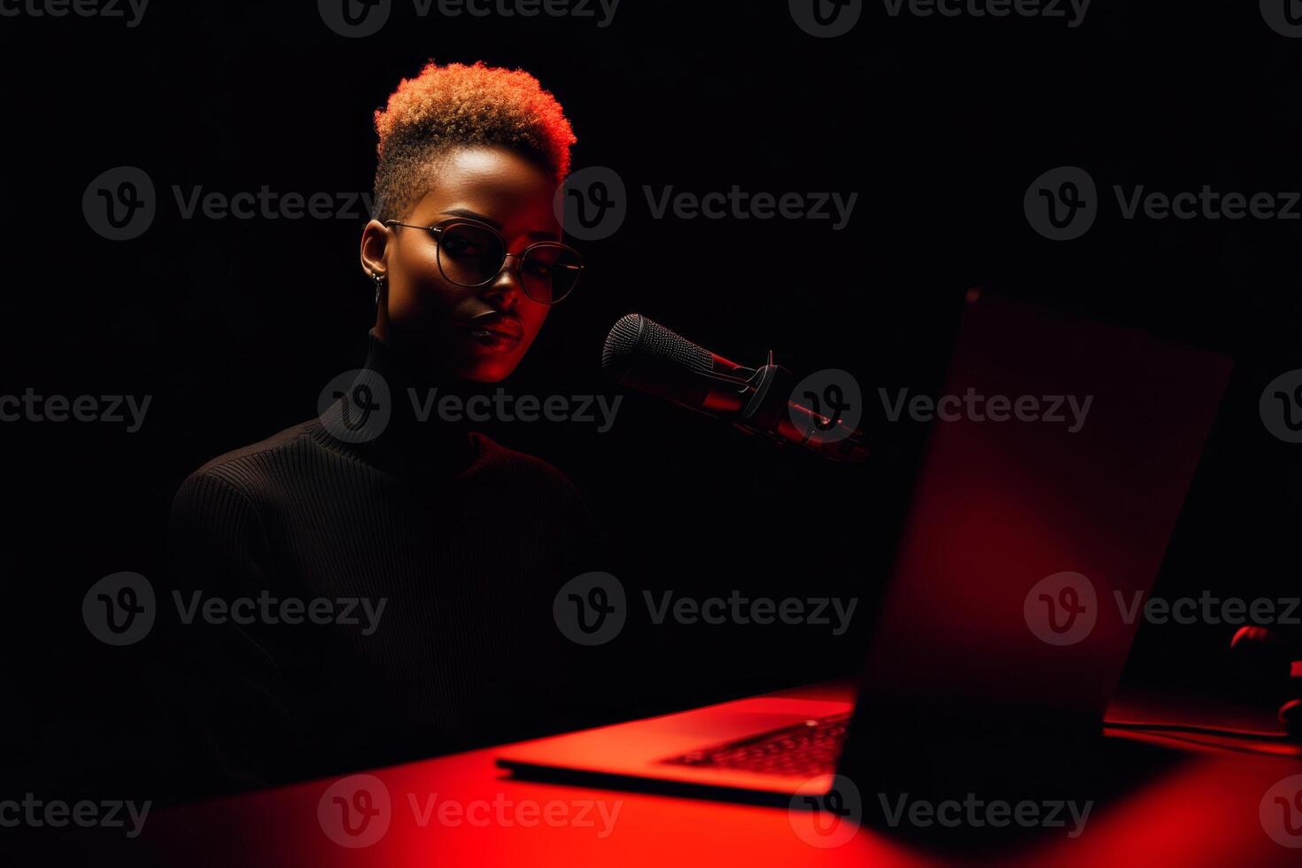 A focused person wearing sunglasses interacts with a laptop while speaking into a microphone. photo
