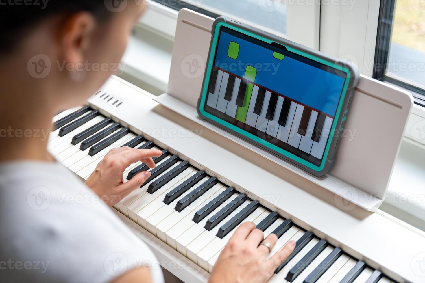 Close up view of young woman learning to play the keyboard at home using an interactive app. Using mobile apps for self-study concept. High quality photo