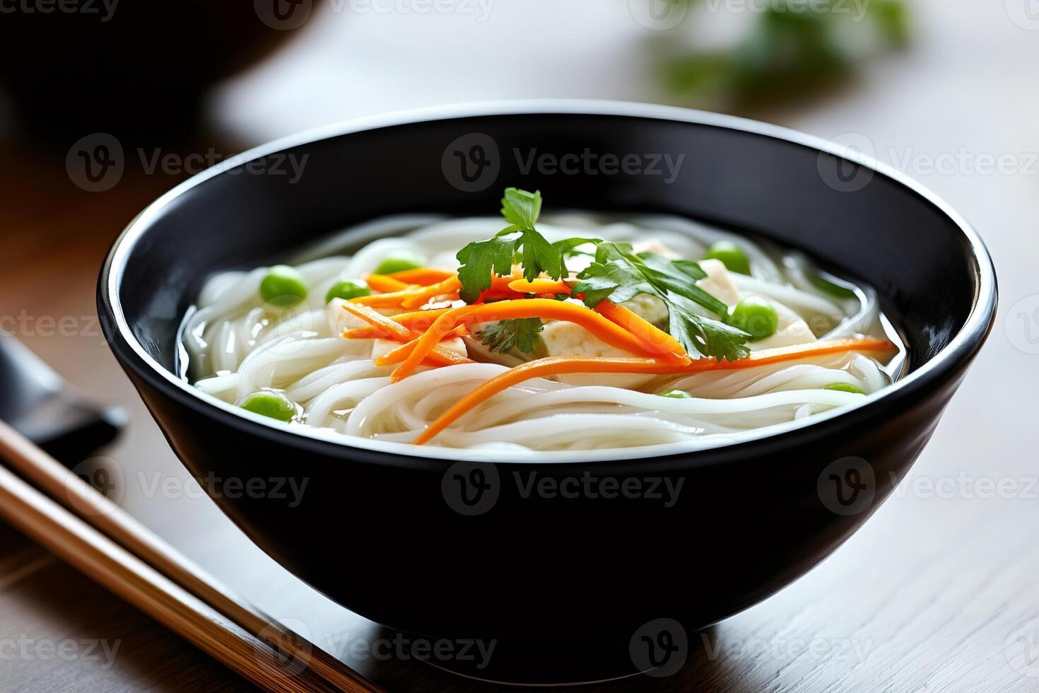 Close up of a bowl of vietnamese pho soup with noodles, tofu, carrots, peas and cilantro photo