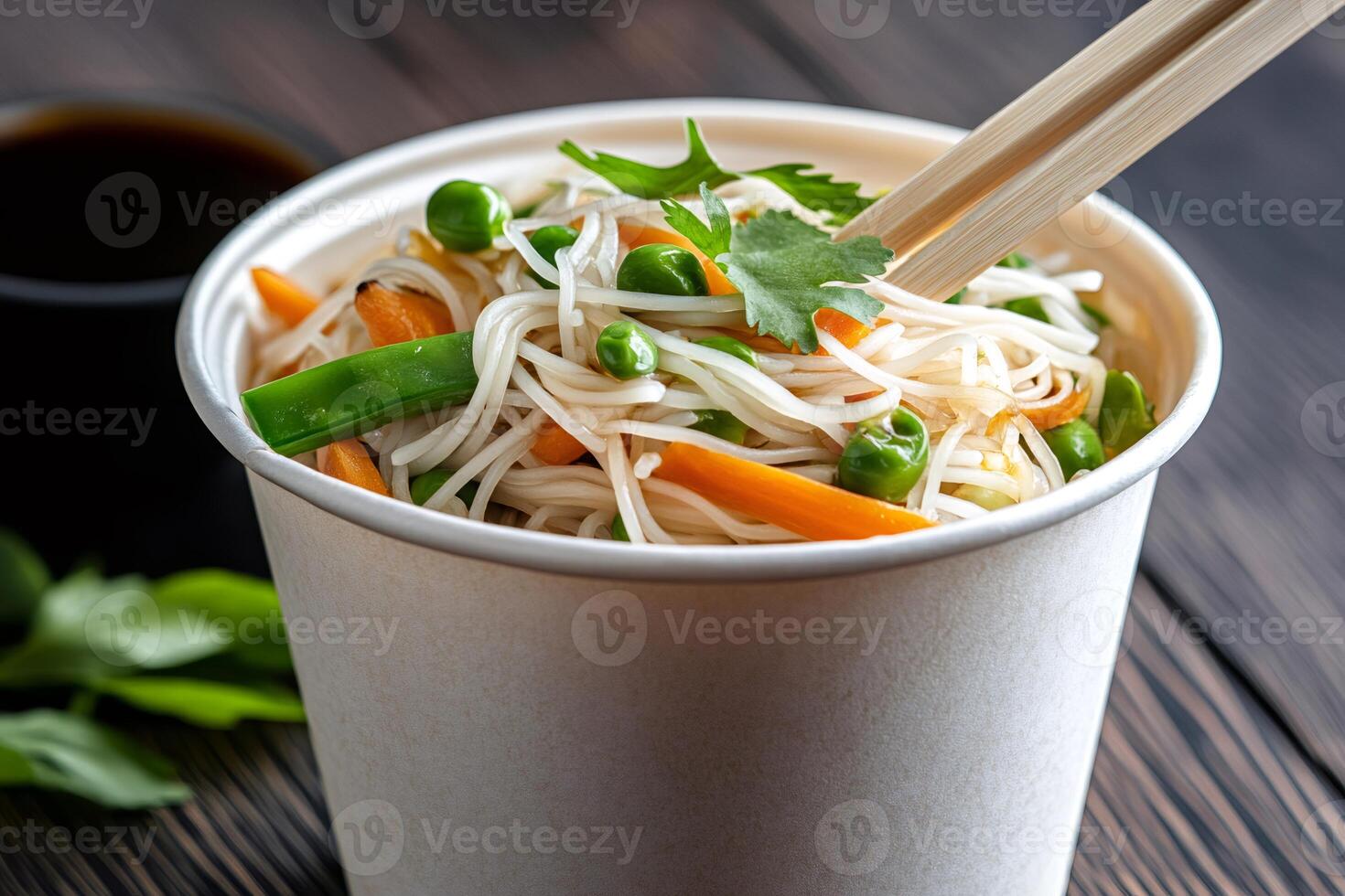 Rice noodles with vegetables and chopsticks in takeaway paper cup photo