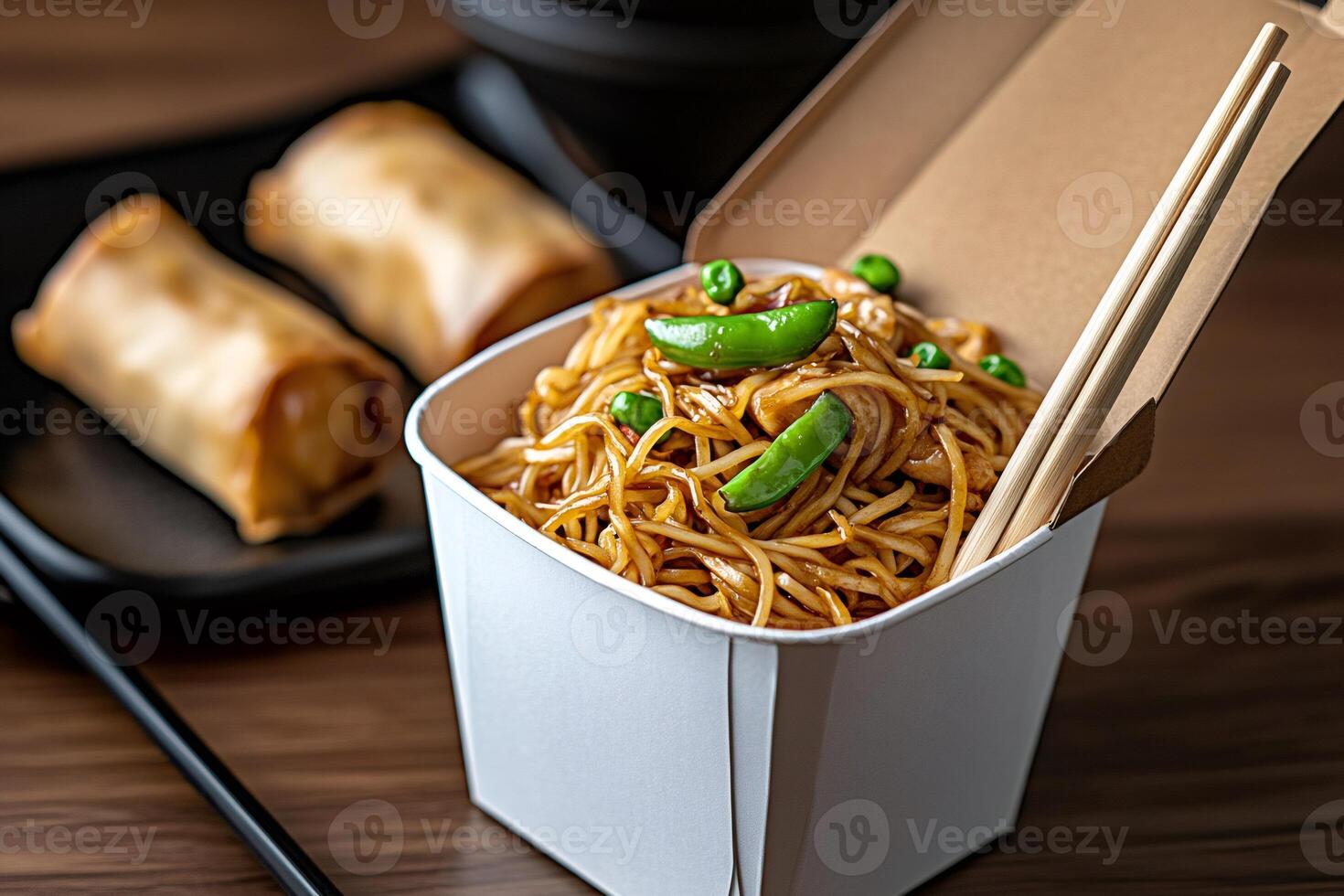 Noodles with chicken and peas in takeaway box with spring rolls and chopsticks photo