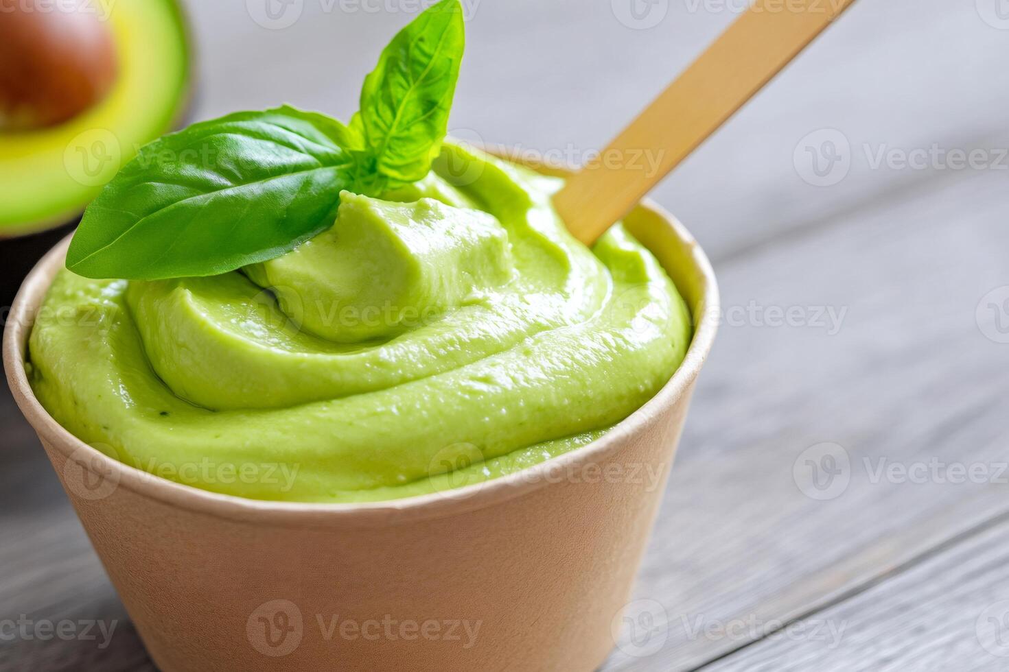 Creamy avocado yogurt decorated with basil leaf in biodegradable cup photo