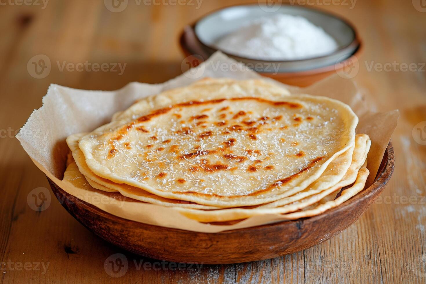 Stack of freshly baked flatbreads sprinkled with desiccated coconut resting in wooden bowl photo