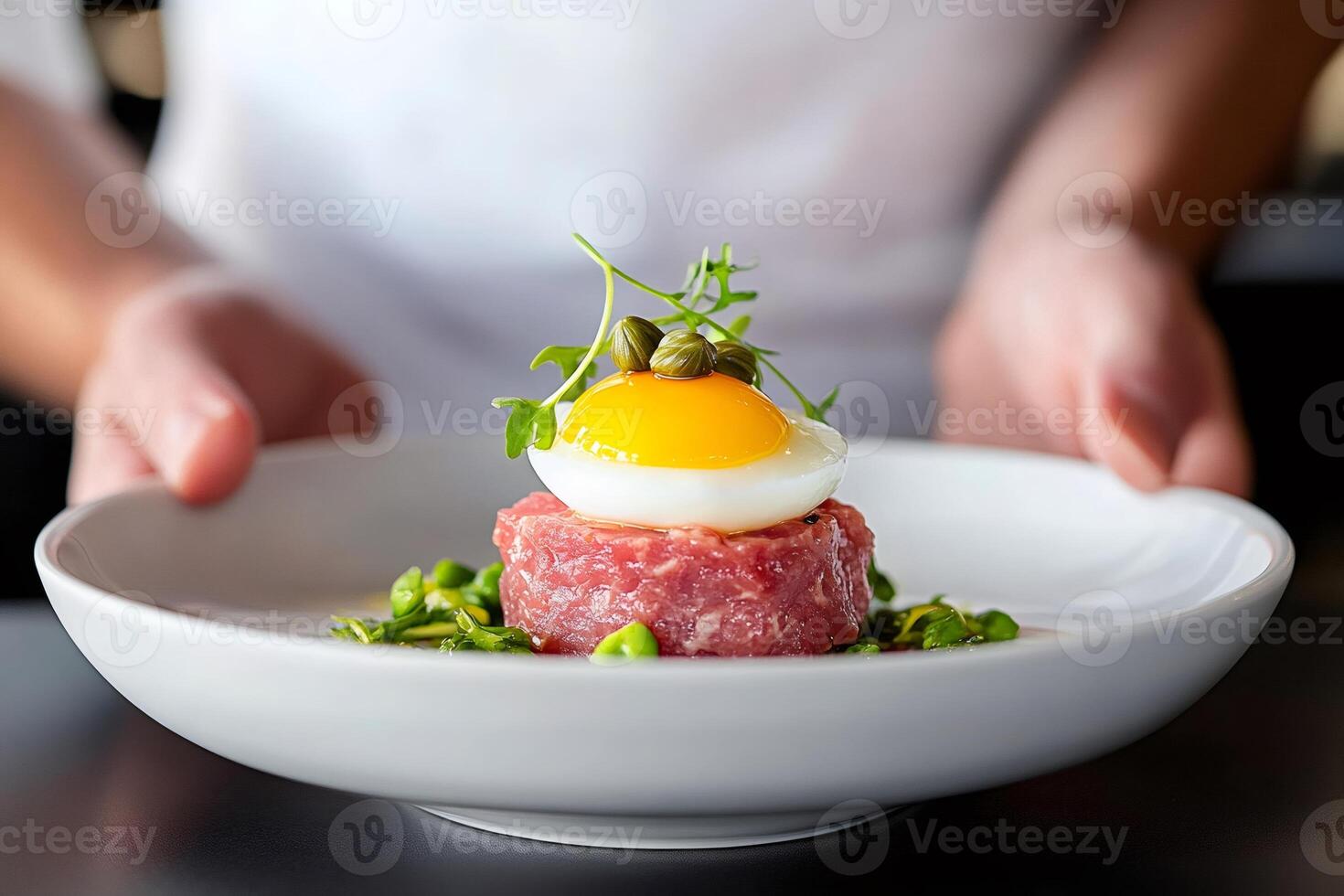 Chef presenting delicious beef tartare with quail egg and capers photo