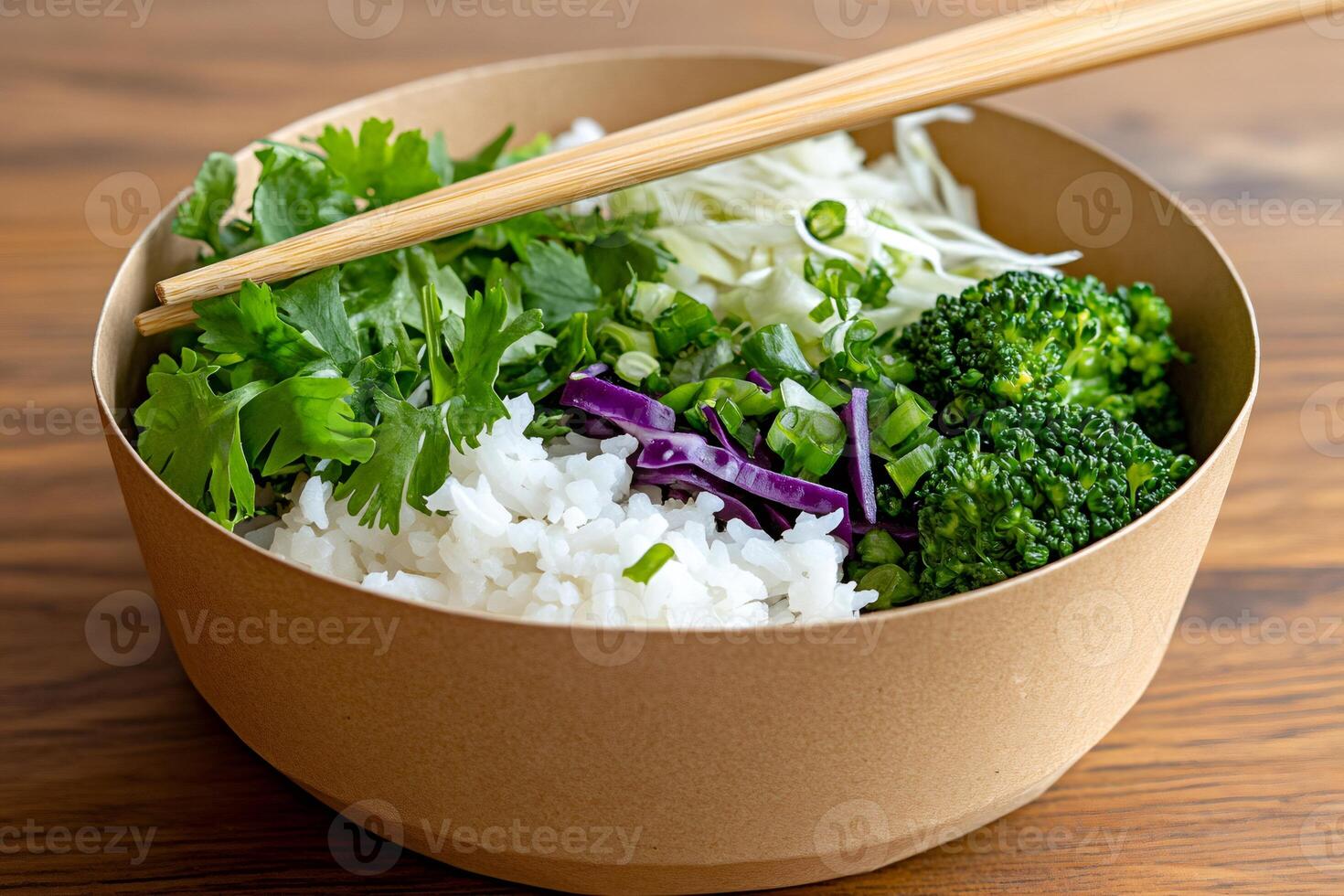 Chopsticks resting on a bowl of rice with coriander, broccoli and red cabbage photo