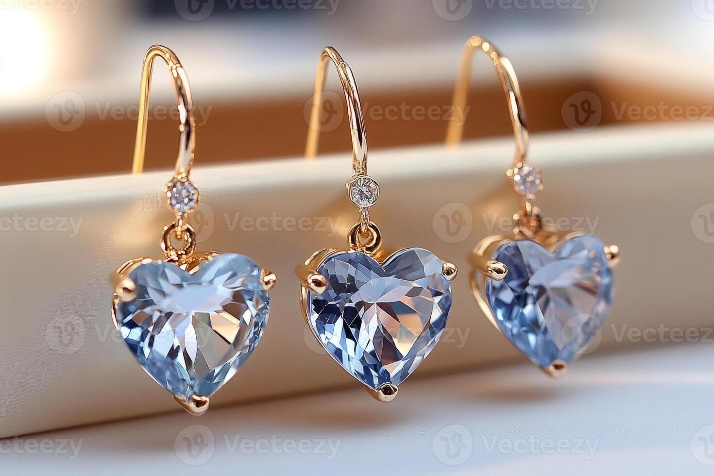 Gold earrings with heart-shaped blue topazes sparkling on light background photo