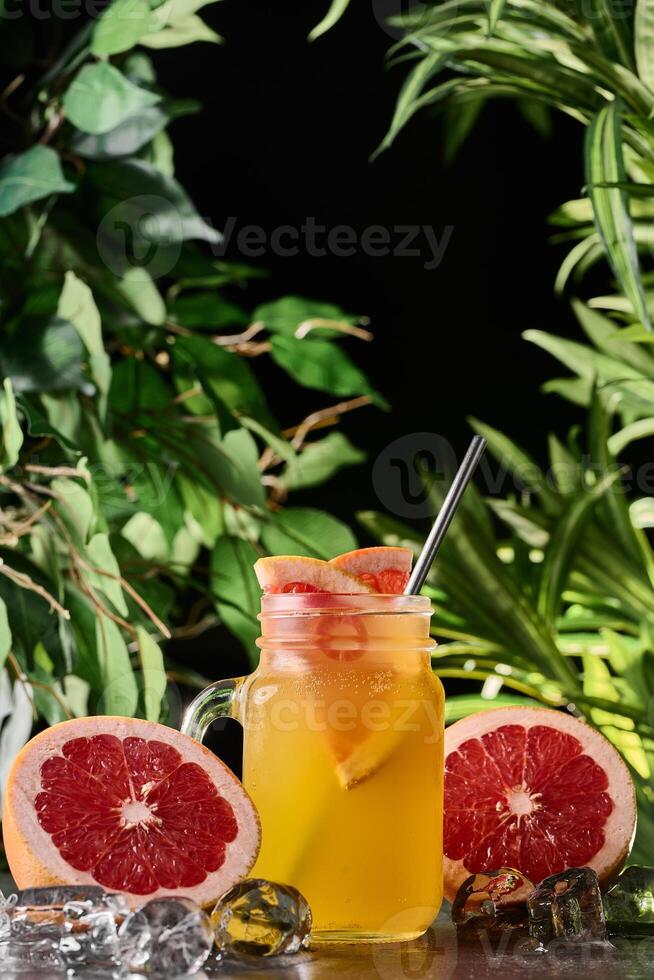 Detox refreshing cocktail from grapefruit and rosemary with ice. Summer drink. Grapefruit lemonade in a glass jar on a dark background. Mason jar photo