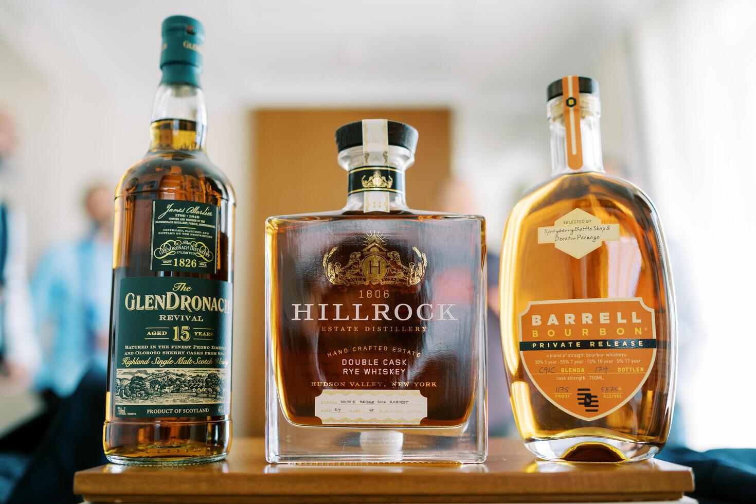 Austin, Texas, USA - April 15, 2024. Bottles of whiskey stand on the table in front of the men. Caption. Glendronach Revival, Hillrock, Barrell Bourbon photo