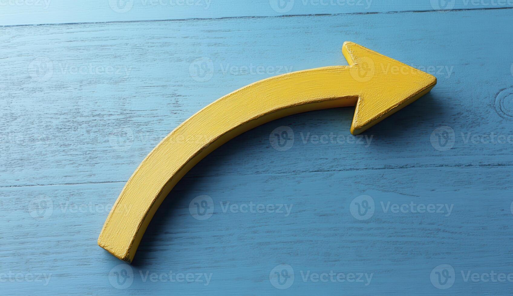 Curved Yellow Arrow on Blue Wood Background photo
