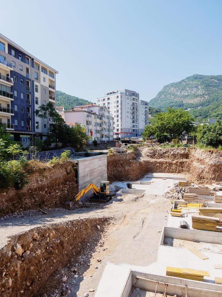Montenegro, Budva - July 04, 2024. Excavator digs the ground at the construction site for the foundation photo