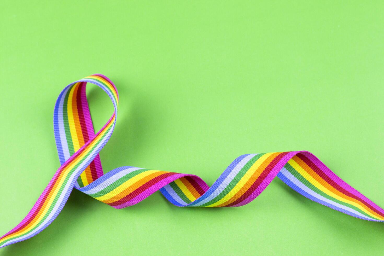 2. Colorful rainbow ribbon strip on green pastel background. Concept of cheering LGBT communities all over the world photo