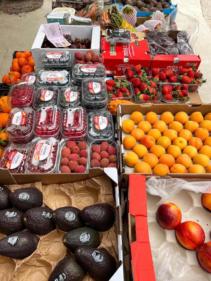 Budva, Montenegro - 25 december 2022. Avocados, peaches, lychee berries, raspberries, strawberries lie in boxes on the market photo