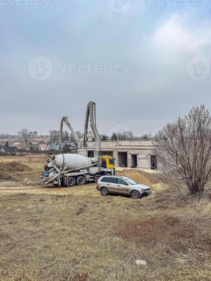 Construction site with a concrete mixer truck and unfinished building in rural area. High quality photo