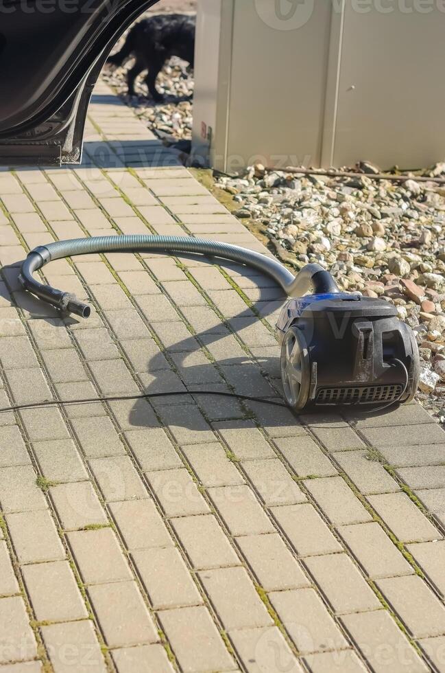 Vacuum cleaner on pavement, used for car cleaning outdoors in sunny weather. High quality photo