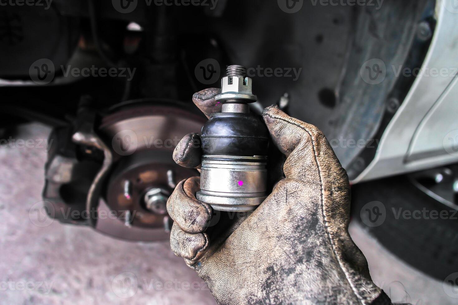Mechanic holding new ball joint for vehicle suspension repair photo