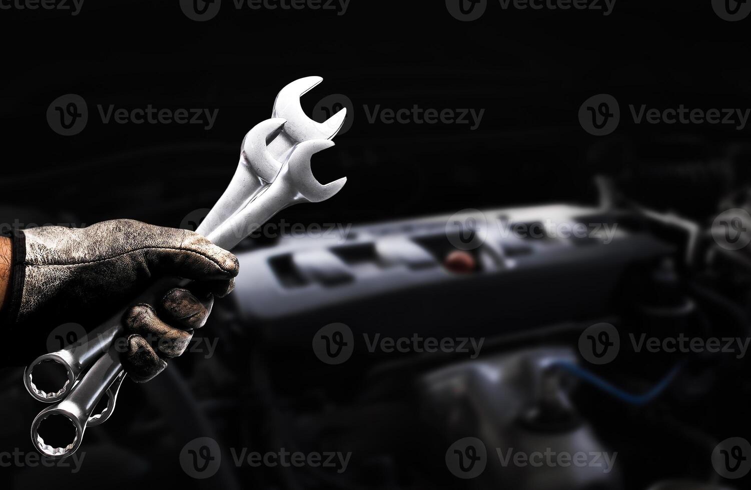 Mechanic holding wrenches during engine maintenance in automotive workshop photo