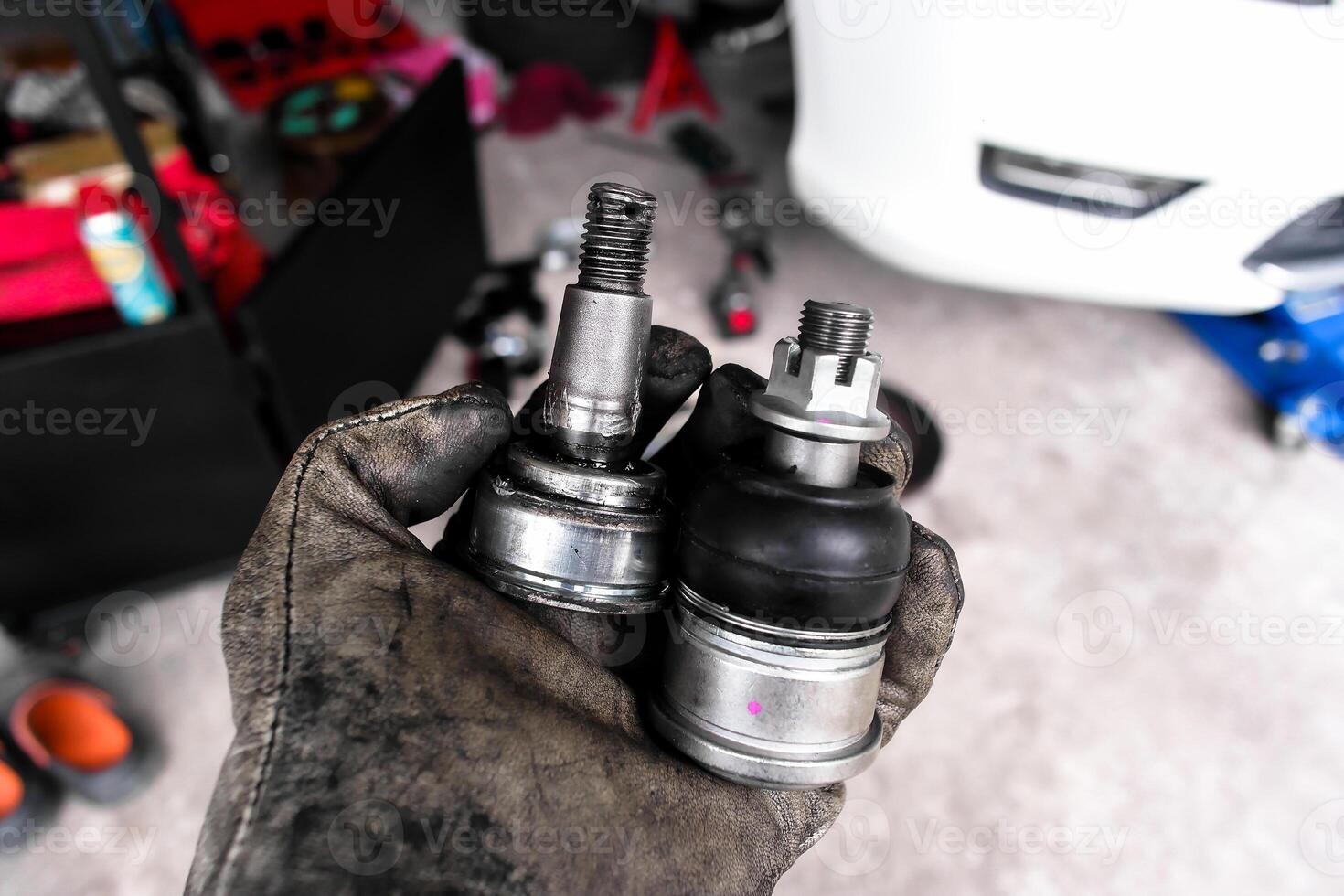Car ball joints comparison new and old , Automotive repair concept. Hand holding two car ball joints for a vehicle suspension. Indoor shot of garage. photo
