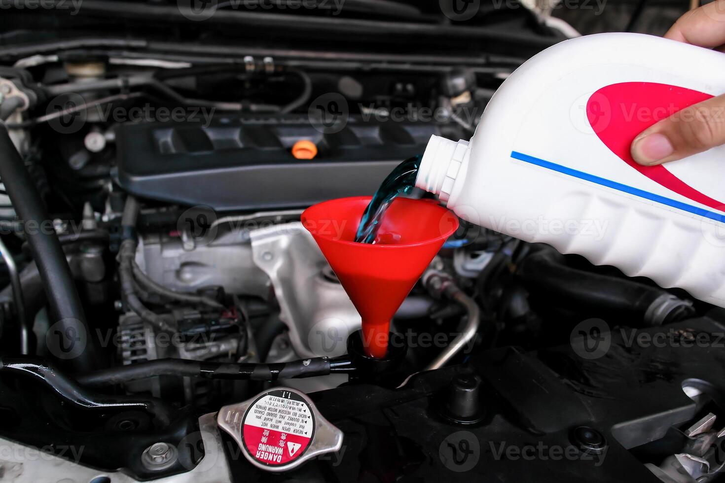 Pouring coolant fluid using a funnel into car radiator , Car maintenance concept photo
